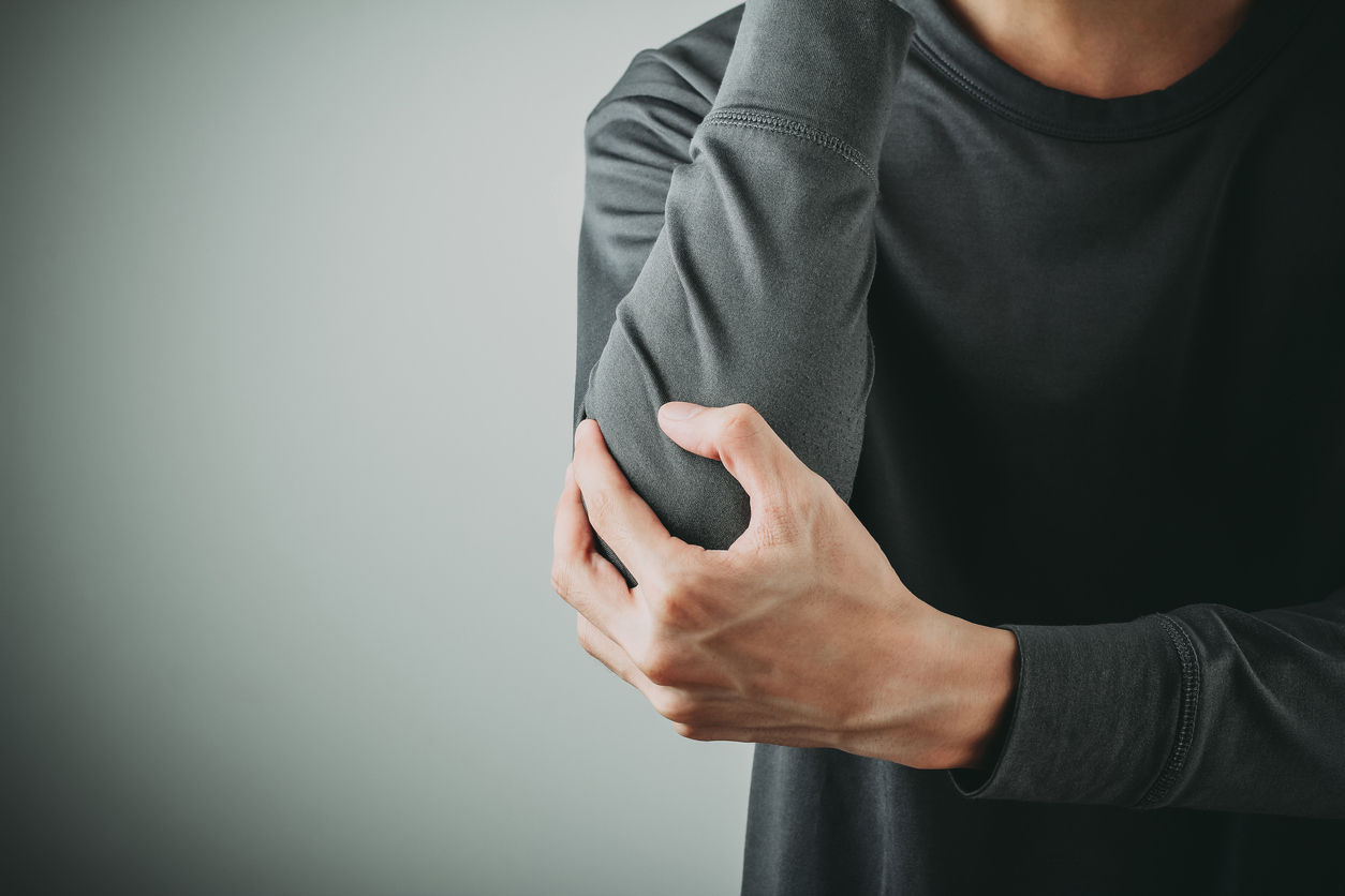 Man holding elbow experiencing tennis elbow pain
